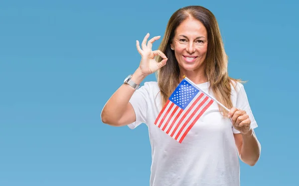 優秀なシンボルの指で サインをして孤立した背景にアメリカ合衆国の国旗を保持している中年ヒスパニック系女性 — ストック写真