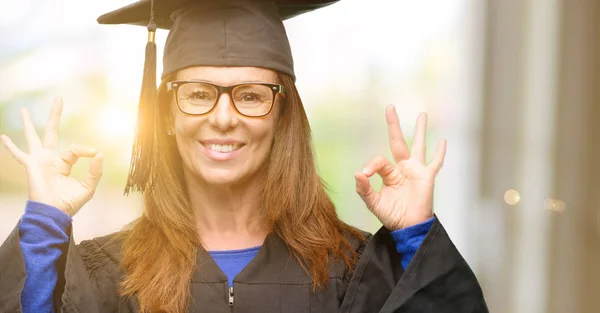 Senior graduate student woman doing ok sign gesture with both hands expressing meditation and relaxation