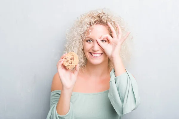 Joven Mujer Rubia Sobre Grunge Gris Pared Comer Chocolate Chip — Foto de Stock