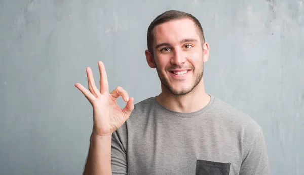 Joven Caucásico Hombre Sobre Gris Grunge Pared Haciendo Signo Con —  Fotos de Stock