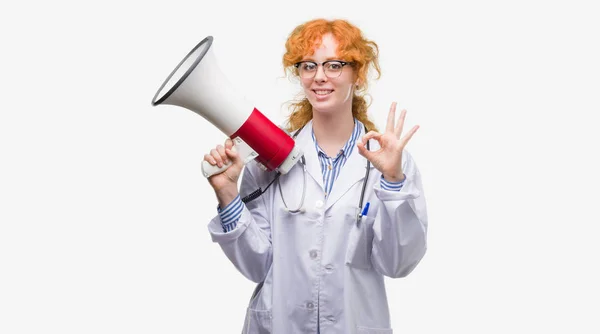 Młoda Ruda Kobieta Lekarz Trzymając Megafon Robi Znak Palcami Doskonały — Zdjęcie stockowe