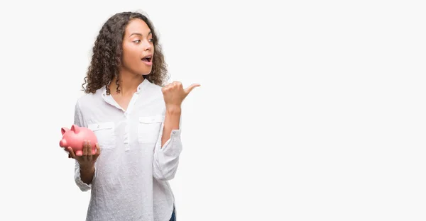 Junge Hispanische Frau Hält Sparschwein Der Hand Und Zeigt Mit — Stockfoto