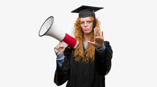 身に着けている赤毛の若い学生女性卒業制服持株メガホン防衛ジェスチャー 深刻な自信を持って式に一時停止の標識をやって開いた手 — ストック写真