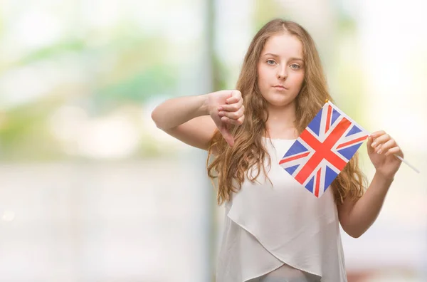 年轻的金发女人拿着英国国旗愤怒的脸 否定的标志显示不喜欢拇指向下 拒绝概念 — 图库照片