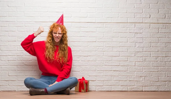 Doğum Günü Şapkası Tuğla Duvar Oturan Genç Kızıl Saçlı Kadın — Stok fotoğraf