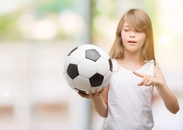 Молодой Блондин Держащий Футбольный Мяч Счастлив Указывая Рукой Пальцем — стоковое фото