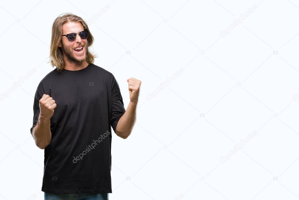 Young handsome man with long hair wearing sunglasses over isolated background very happy and excited doing winner gesture with arms raised, smiling and screaming for success. Celebration concept.