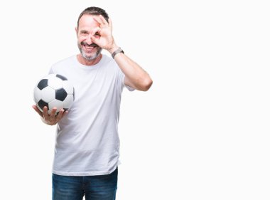 Orta yaş ağarmış komuta sizde futbol futbol topu ile mutlu yüz el parmaklarının arasından seyir göz üzerinde ok işaretiyle yapıyor gülümseyen izole arka plan üzerinde tutan