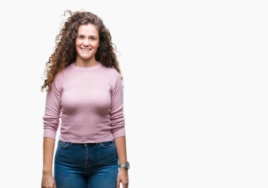 Güzel esmer kıvırcık saçlı Genç kız yüzünde mutlu ve güzel bir gülümseme ile izole arka plan üzerinde pembe kazak giyiyor. Şanslı kişi.