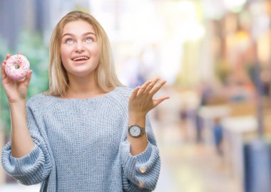 Kocaman bir gülümseme ile çığlık zaferini kutluyor ve ellerini kaldırdı izole arka plan çok mutlu ve heyecanlı, kazanan ifade üzerinde tatlı çörek yiyen genç kafkas kadın