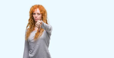 Mutsuz ve kızgın ret gösterilen ve başparmak aşağı hareketi ile negatif arayan genç Kızıl saçlı kadın. Kötü ifade.