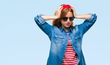 Genç güzel kadın giyiyor güneş gözlüğü çünkü umutsuz ve stresli baş ağrısı acı acı izole arka plan ve migren yüzünden. Ellerini kafasına.