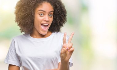 Mutlu yüz zafer işareti yaparken kameraya göz kırpıyor ile gülümseyen izole arka plan üzerinde genç afro Amerikalı kadın. İki numaralı.