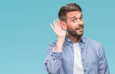 Bir işitme söylenti ya da dedikodu için dinleme kulak üzerinde el ile gülümseyen izole arka plan üzerinde beyaz t-shirt giyen genç yakışıklı adam. Sağırlık kavramı.