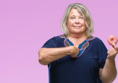 Kıdemli artı boyutu ile arka plan beyaz kadın üzerinde şeker donut yemek izole için kendini parmakla yüz sürpriz