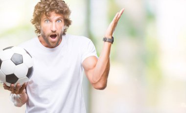 İspanyol yakışıklı modeli futbol futbol topu tutan kocaman bir gülümseme ile çığlık zaferini kutluyor arka plan çok mutlu ve heyecanlı, kazanan ifade izole ve ellerini kaldırdı