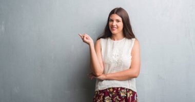 Grunge gri duvar el ve parmak ile tarafına işaret çok mutlu genç esmer kadın