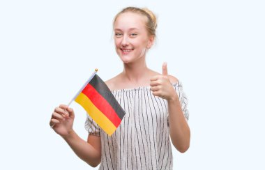 Sarışın genç kadın holding bayrak Almanya ok işareti yapıyor büyük gülümseme ile mutlu parmak ile mükemmel işaret parmak