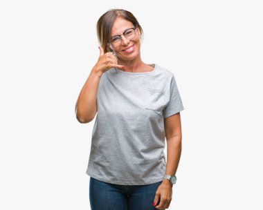 Orta yaş üst düzey İspanyol kadın yapıyor gülümseyen izole arka plan üzerinde gözlük telefon hareketi ile el ve parmak telefonda konuşuyor gibi. Kavramları iletişim.