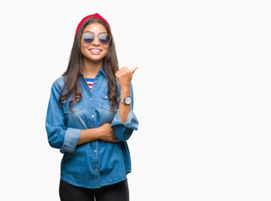 Genç güzel Arap kadın arıyorum ve başparmak yanında yukarıyı mutlu yüz ile gülümseyen izole arka plan üzerinde güneş gözlüğü takıyor.
