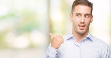 Seyir ve başparmak yanında yukarıyı mutlu yüz ile gülümseyen yakışıklı genç işadamı.