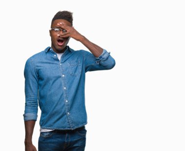 Genç Afro-Amerikan adam utanç ifadesi ile parmaklarımın arasından bakan yüz ve gözler el ile kapsayan şok bakmak izole arka plan üzerinde.