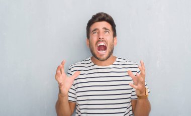 Donanma t-shirt çılgın ve kızgın bağırarak ve agresif ifade ve silah kaldırdı bağırmaya gri grunge duvarın üzerinden yakışıklı genç adam. Hayal kırıklığı kavramı.