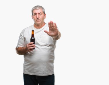 Üst düzey yakışıklı açık eliyle dur işareti ile ciddi ve kendine güvenen ifade, savunma jest yapıyor izole arka plan üzerinde bira şişesi içme