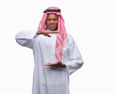 Geleneksel keffiyeh ile büyük ve büyük boy işaret, ölçü birimi sembol gösteren el eller izole arka plan üzerinde giyen genç Arapça Afrika adam. Kameraya bakarak gülümsüyordu. Ölçüm kavramı.