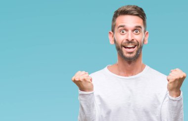 İzole arka plan kutlama üzerinde genç yakışıklı adam şaşırttı ve başarı için kaldırdı kollarını açarak hayret ve gözleri açık. Kazanan kavramı.