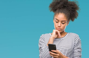 Genç afro Amerikalı kadın manifatura Smartphone izole arka plan ciddi bir yüz düşünme hakkında soru, çok karışık bir fikir üzerinde kullanma