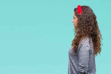 Güzel esmer kıvırcık saç üzerinde çizgili süveter giyen genç kız tarafına, seyir arka plan izole dinlenmek doğal yüz emin gülümseme ile pozuyla profili.