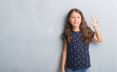 Genç İspanyol çocuğun gösterilen ve parmakları ile işaret grunge gri duvarın üzerinden dört kendinden emin ve mutlu gülümseyerek iken numara.