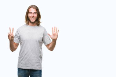 Gösterilen ve parmakları ile işaret izole arka plan üzerinde uzun saçlı Genç yakışıklı adam kendinden emin ve mutlu gülümseyerek süre yedi numara.