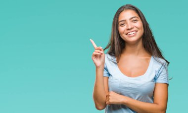 Yüzünde kocaman bir gülümseme ile izole arka plan üzerinde genç güzel Arap kadın kameraya bakarak yan el ve parmak ile işaret.