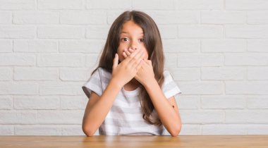 Evde masaya oturan genç İspanyol çocuğu kapsayan ağız elle hata için şok. Gizli kavramı.