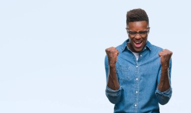 İzole arka plan kutlama üzerinde genç Afro-Amerikan adam şaşırttı ve başarı için kaldırdı kollarını açarak hayret ve gözleri açık. Kazanan kavramı.