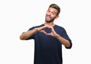 Genç yakışıklı adam aşık kalp simgesi ve elleriyle şekil gösteren gülümseyen izole arka plan üzerinde kış kazak giyiyor. Romantik kavramı.