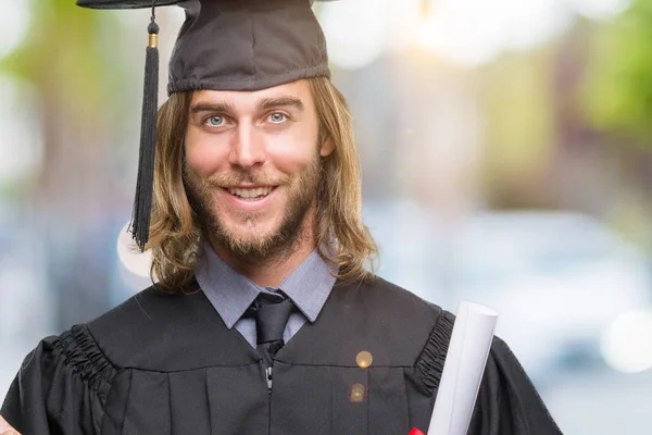 若いハンサムな側の手と指で指す非常に幸せな孤立の背景の上の学位を保持する長い髪で男を卒業します — ストック写真