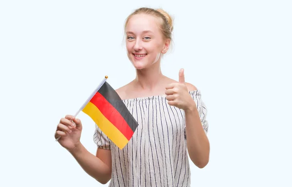 優秀な兆候の指で サインをしている笑顔に満足してドイツのブロンド十代の若者女性保持フラグが親指 — ストック写真