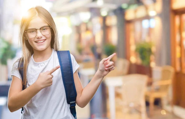 Young beautiful smart student girl wearing backpack over isolated background smiling and looking at the camera pointing with two hands and fingers to the side.