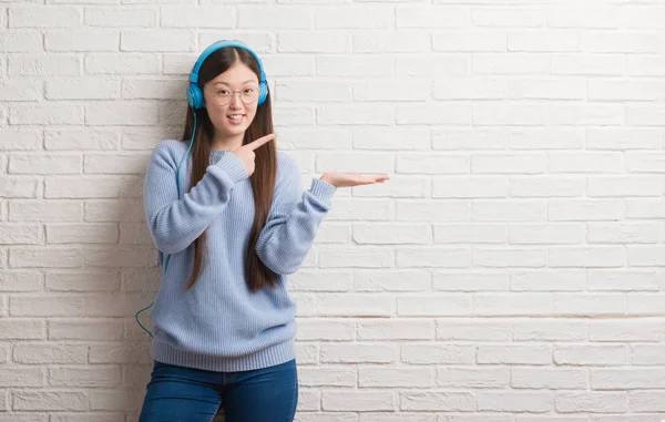 Unga Kinesiska Kvinnan Över Tegelvägg Bär Hörlurar Mycket Glad Pekar — Stockfoto