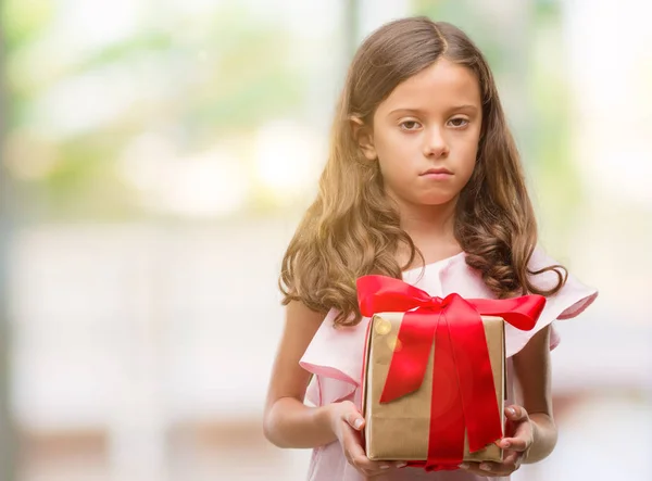 Brunette Hispanic Girl Holding Gift Confident Expression Smart Face Thinking — Stock Photo, Image