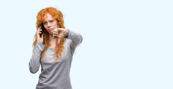 怒った顔 ダウン親指で嫌悪感を示すマイナス記号 拒絶反応の概念と電話で話している若い赤毛の女性 — ストック写真