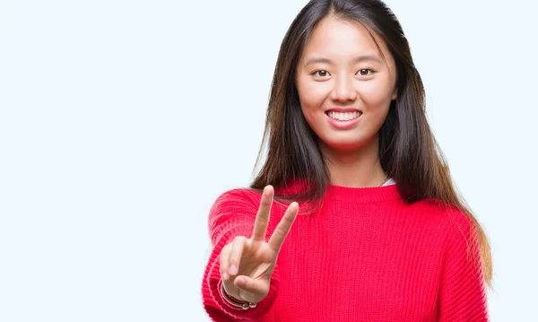 勝利のサインをやって指を表示するカメラを笑みを浮かべて隔離された背景に冬のセーターを着た若いアジア女性 — ストック写真