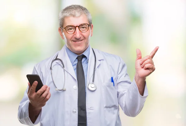 英俊的资深医生男子发短信发送消息使用 Smarpthone 在孤立的背景非常愉快的指向与手和手指的一侧 — 图库照片