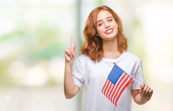 Young beautiful woman holding flag of america over isolated background surprised with an idea or question pointing finger with happy face, number one