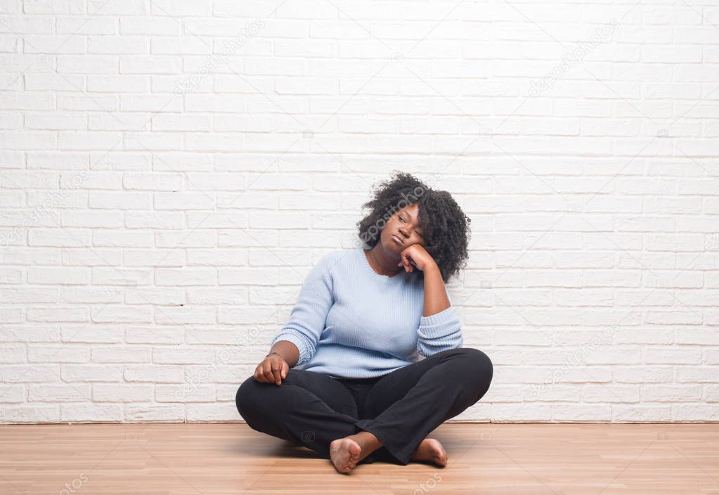 Young african american woman sitting on the floor at home thinking looking tired and bored with depression problems with crossed arms.