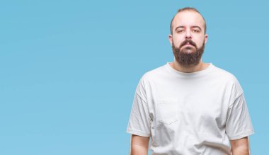 Yüzünde ciddi bir ifade ile izole arka plan üzerinde rahat t-shirt giyen genç beyaz hipster adam. Basit ve doğal kameraya bakıyor.