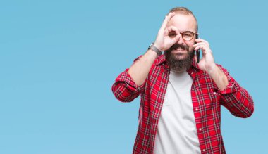 Smartphone ile mutlu yüz el parmaklarının arasından seyir göz üzerinde ok işaretiyle yapıyor gülümseyen izole arka plan üzerinde konuşan genç beyaz hipster adam